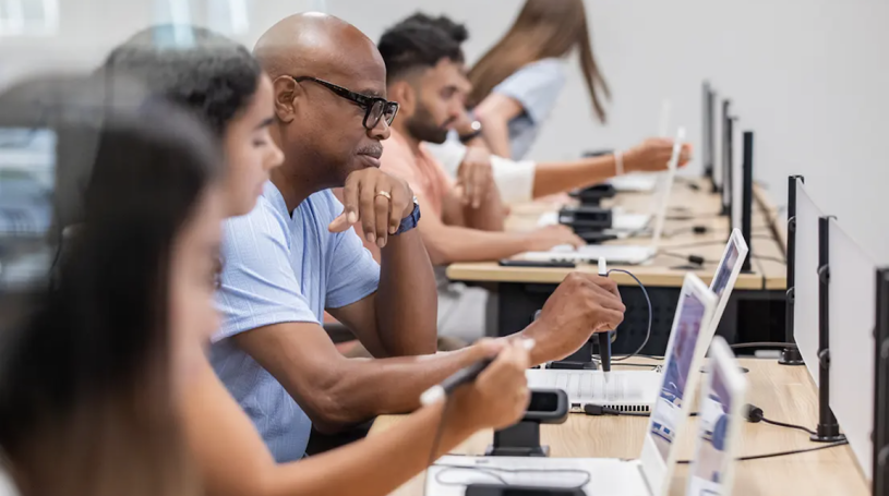Students seated at laptops in a classroom during a cybersecurity training session